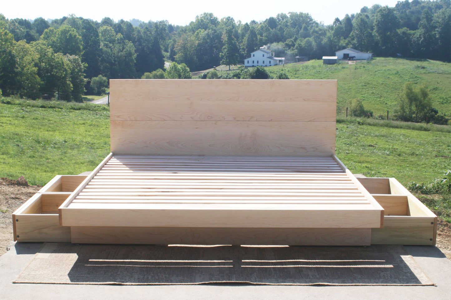Wooden bed frame with storage drawers in a rural setting