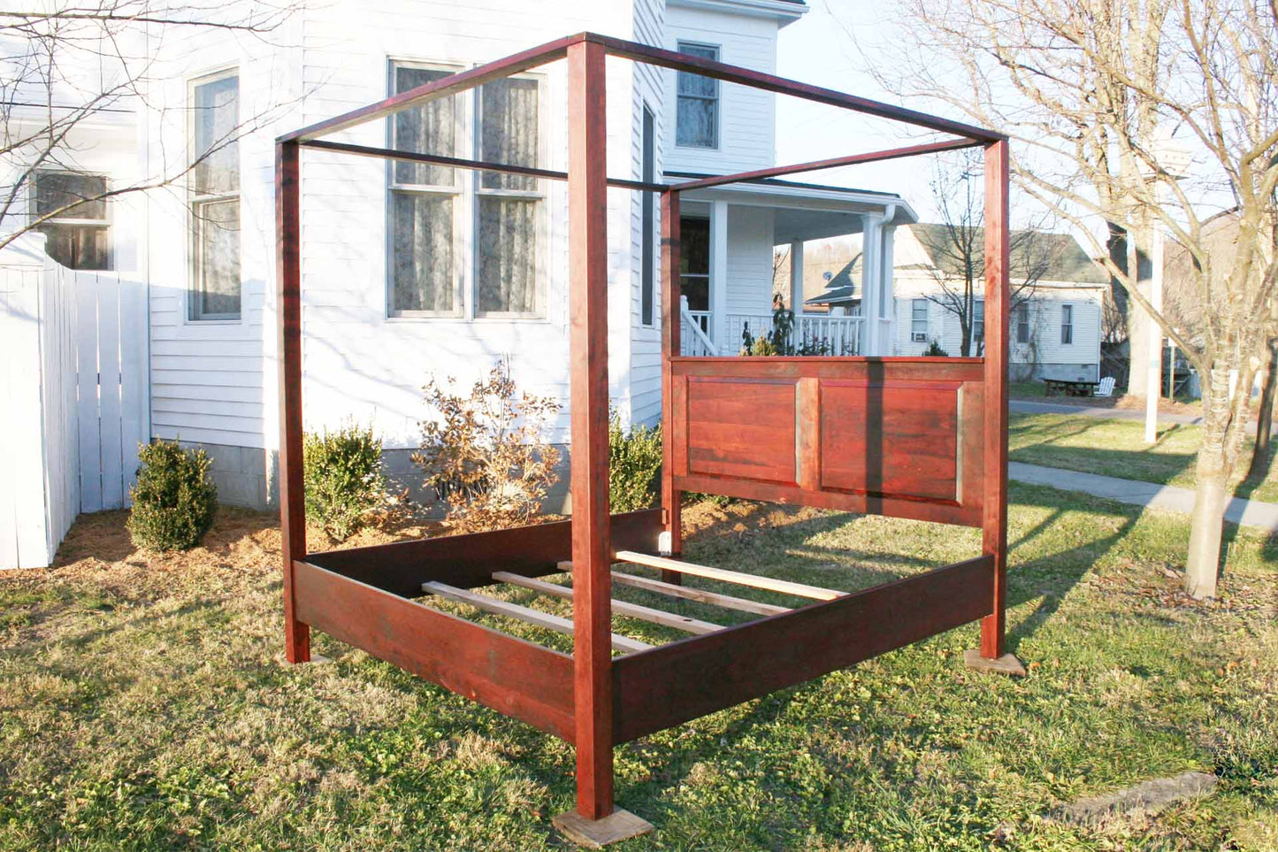 angled view hardwood canopy bed with straight posts and paneled headboard