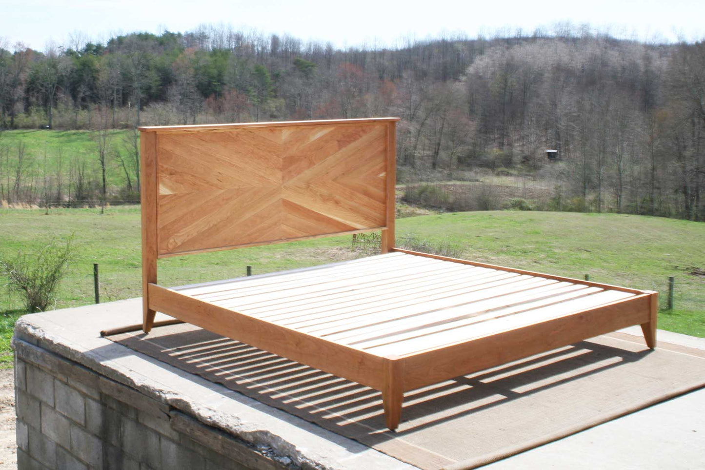 Platform Bed with headboard in herringbone style light colored side angled view