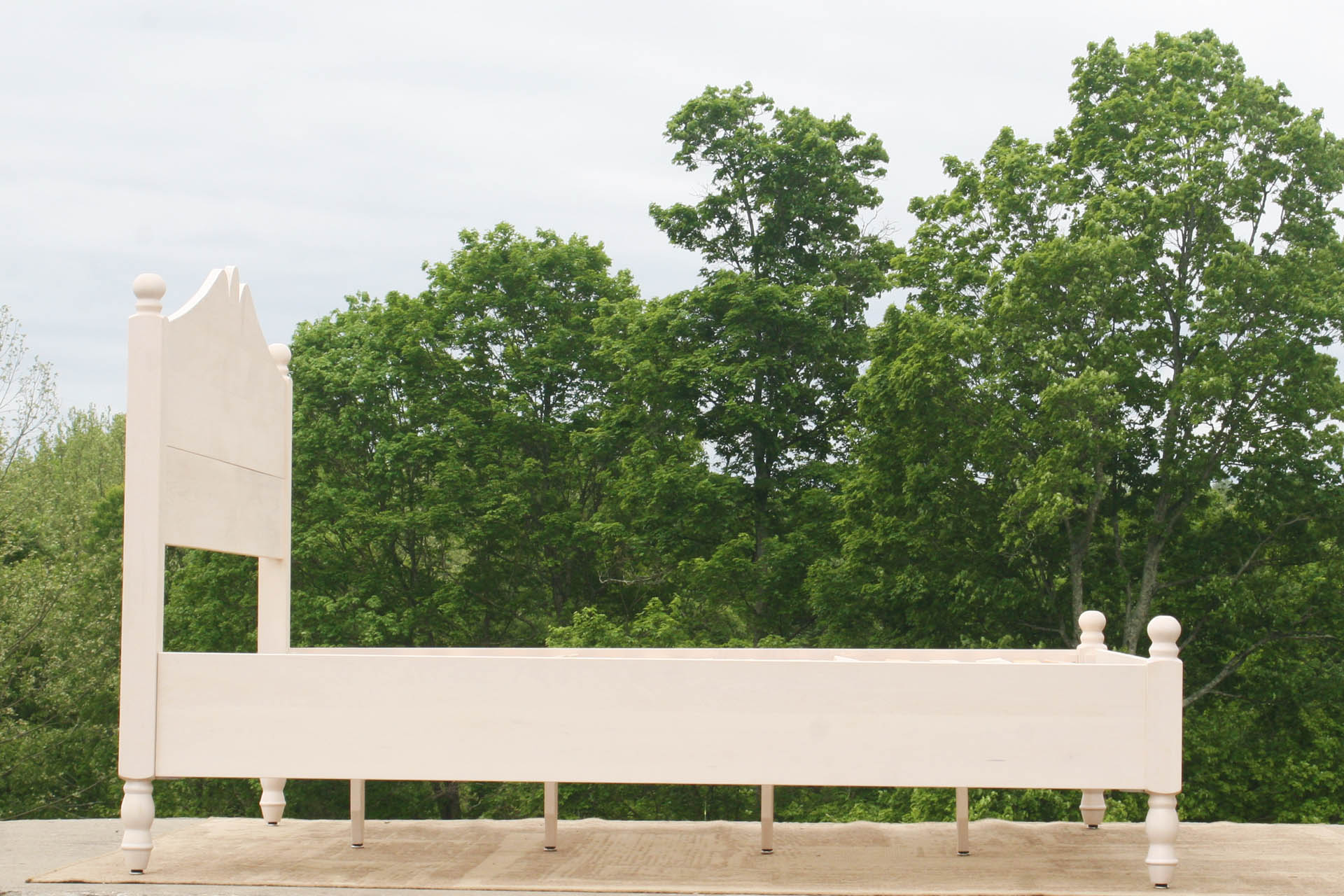 Classic four poster bed with turned posts and scrolled headboard side view
