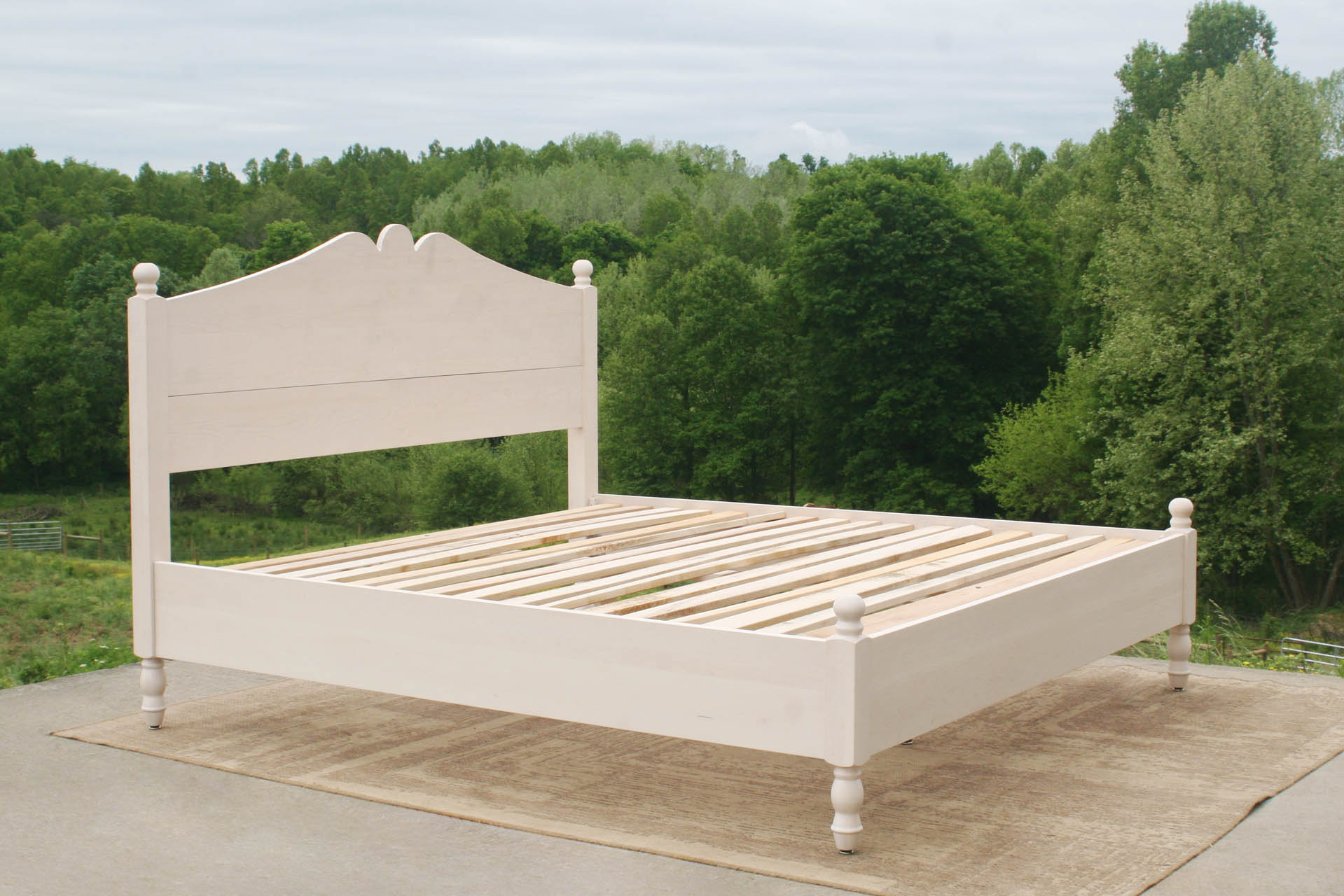 Classic four poster bed with turned posts and scrolled headboard angled view