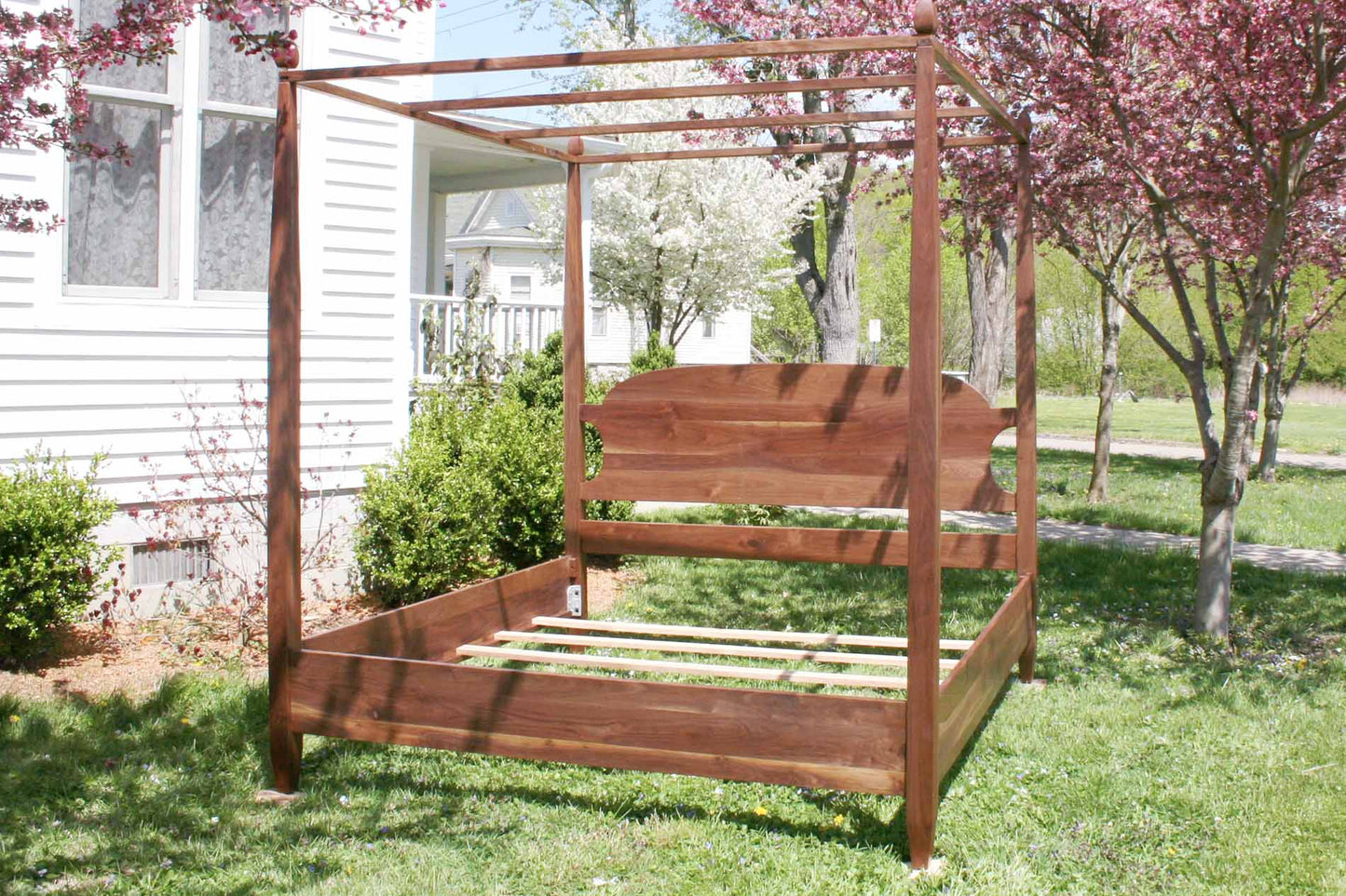 canopy bed with tapered posts and curved headboard front angled view