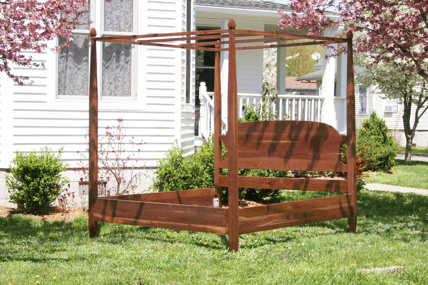 angled view hardwood canopy bed with tapered posts and curved headboard