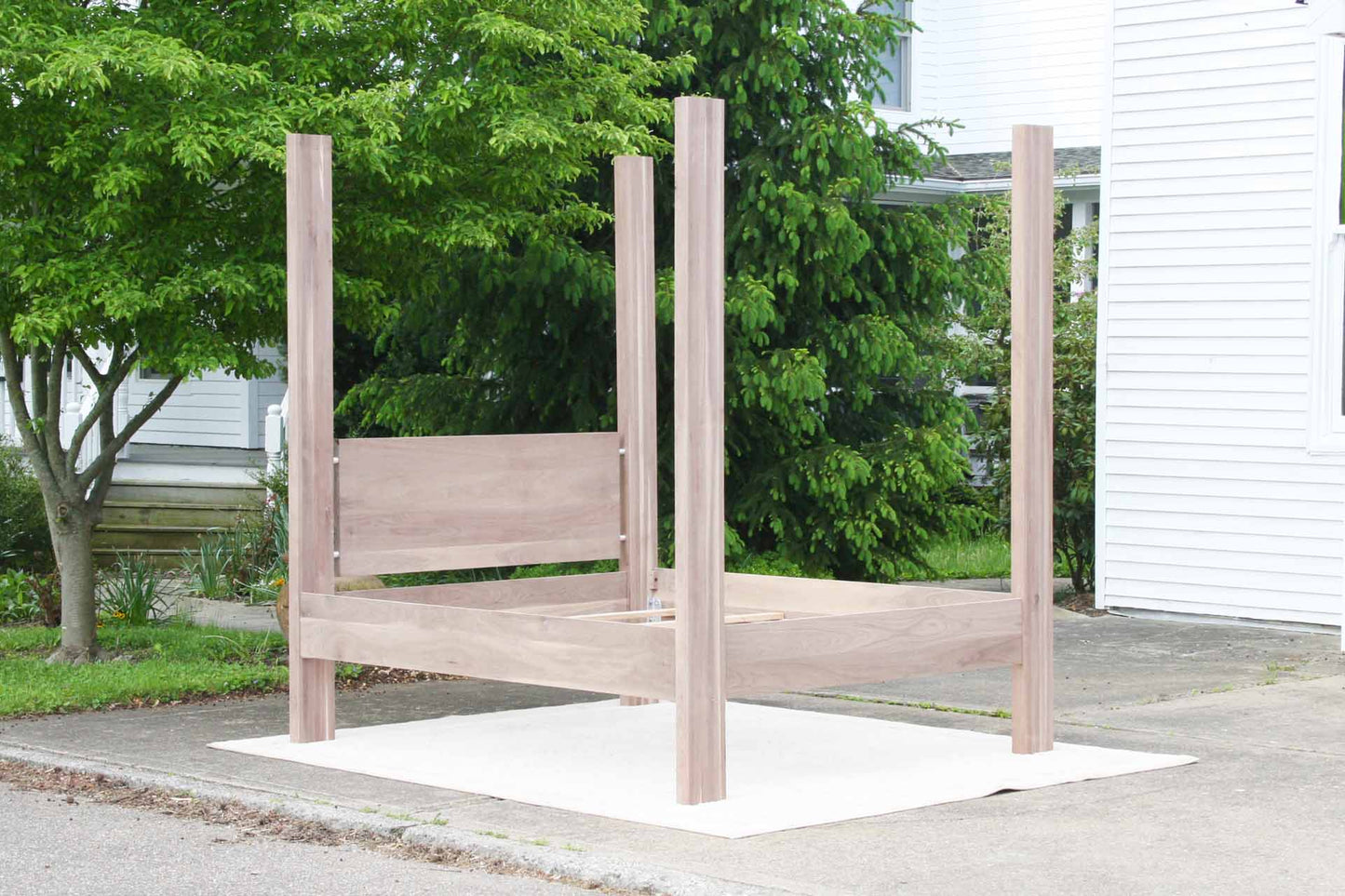 angled view four poster bed with large straight posts and headboard