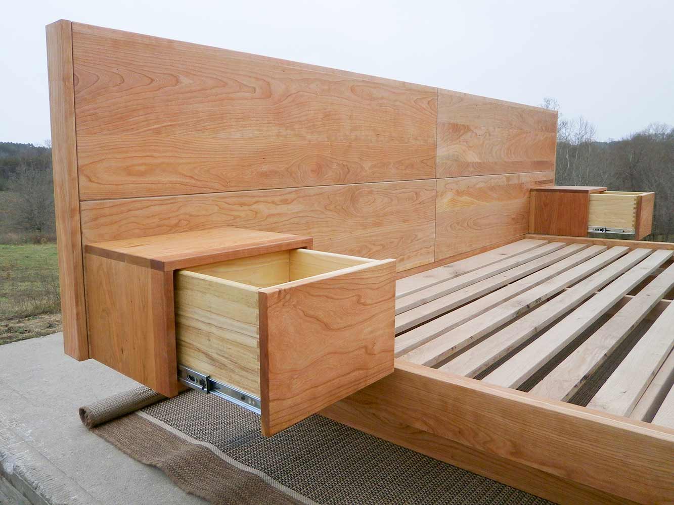 close up of low platform bed with wide headboard attached tables and angled base frame