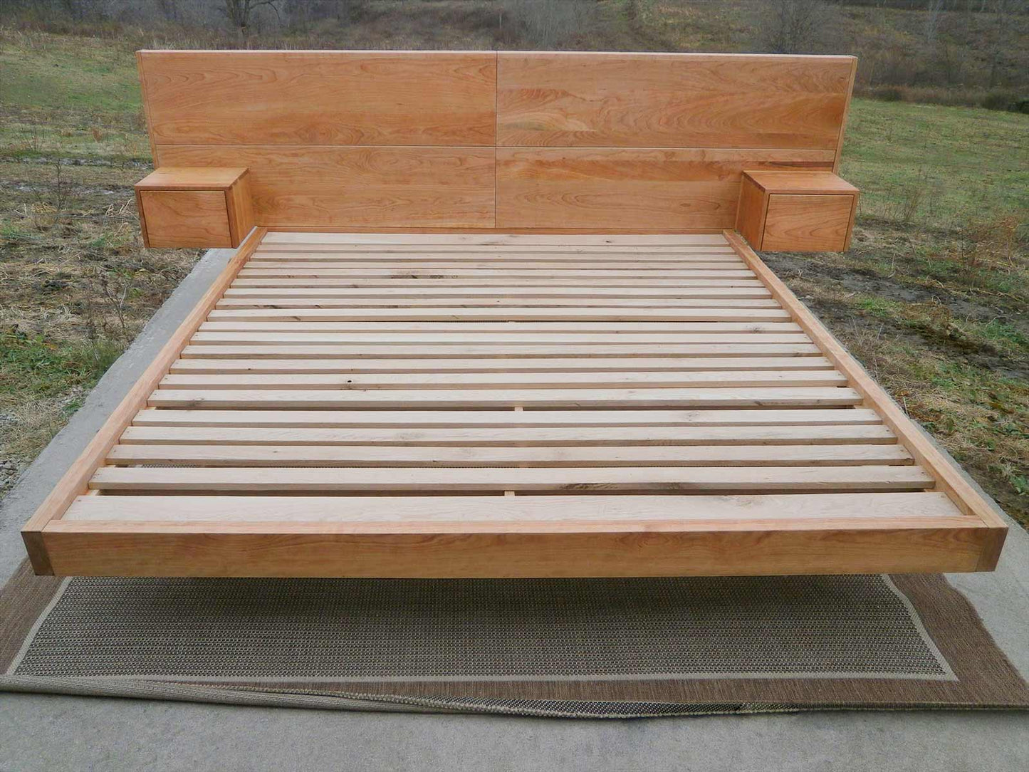low platform bed with wide headboard attached tables and angled base frame front view