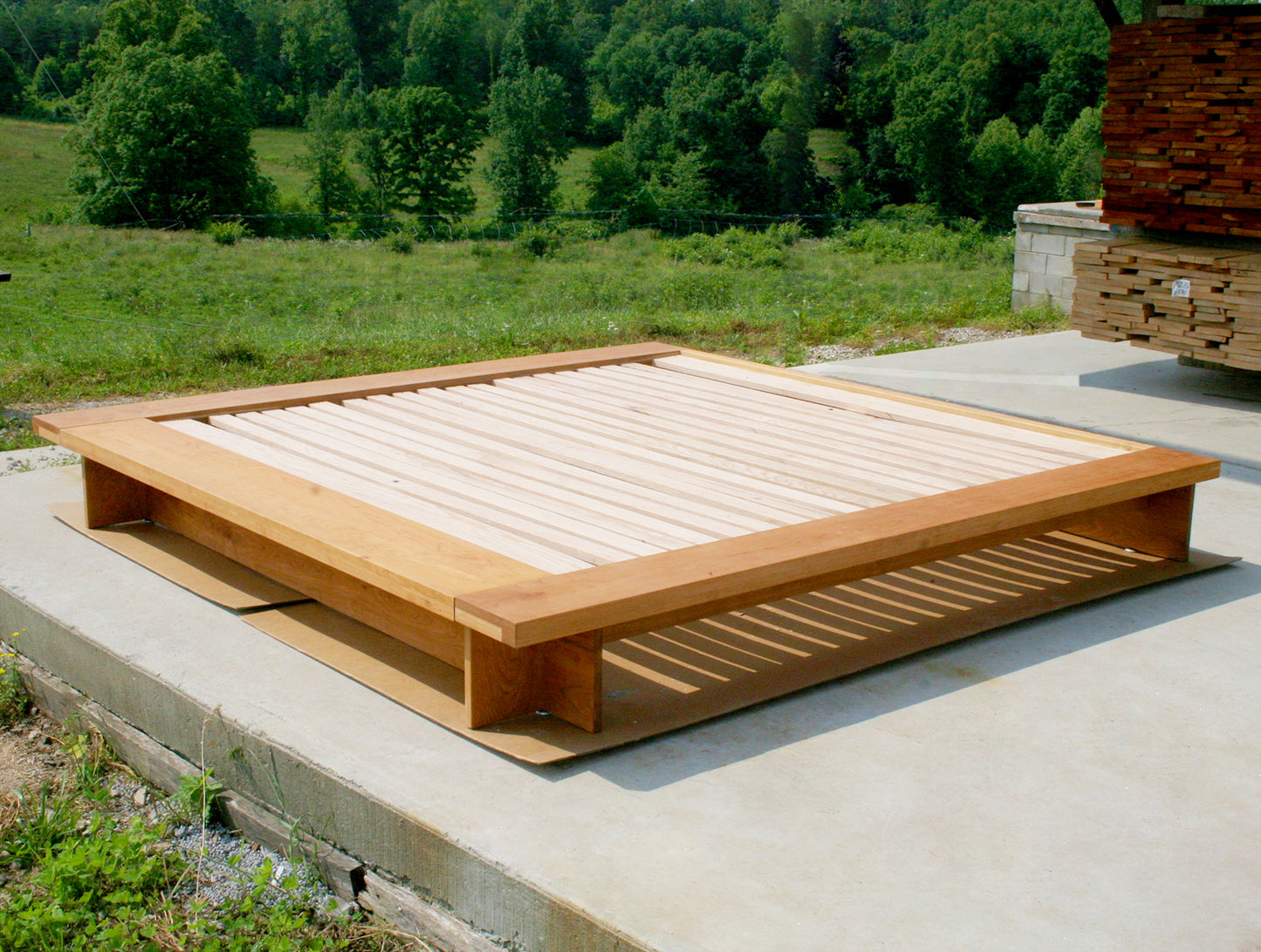 angled view natural hardwood low platform bed with wide platform and optional side tables