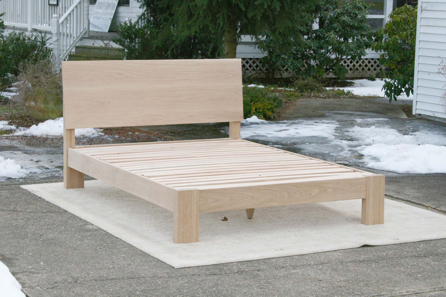 sturdy platform bed with angled headboard and wide thick posts angled side view