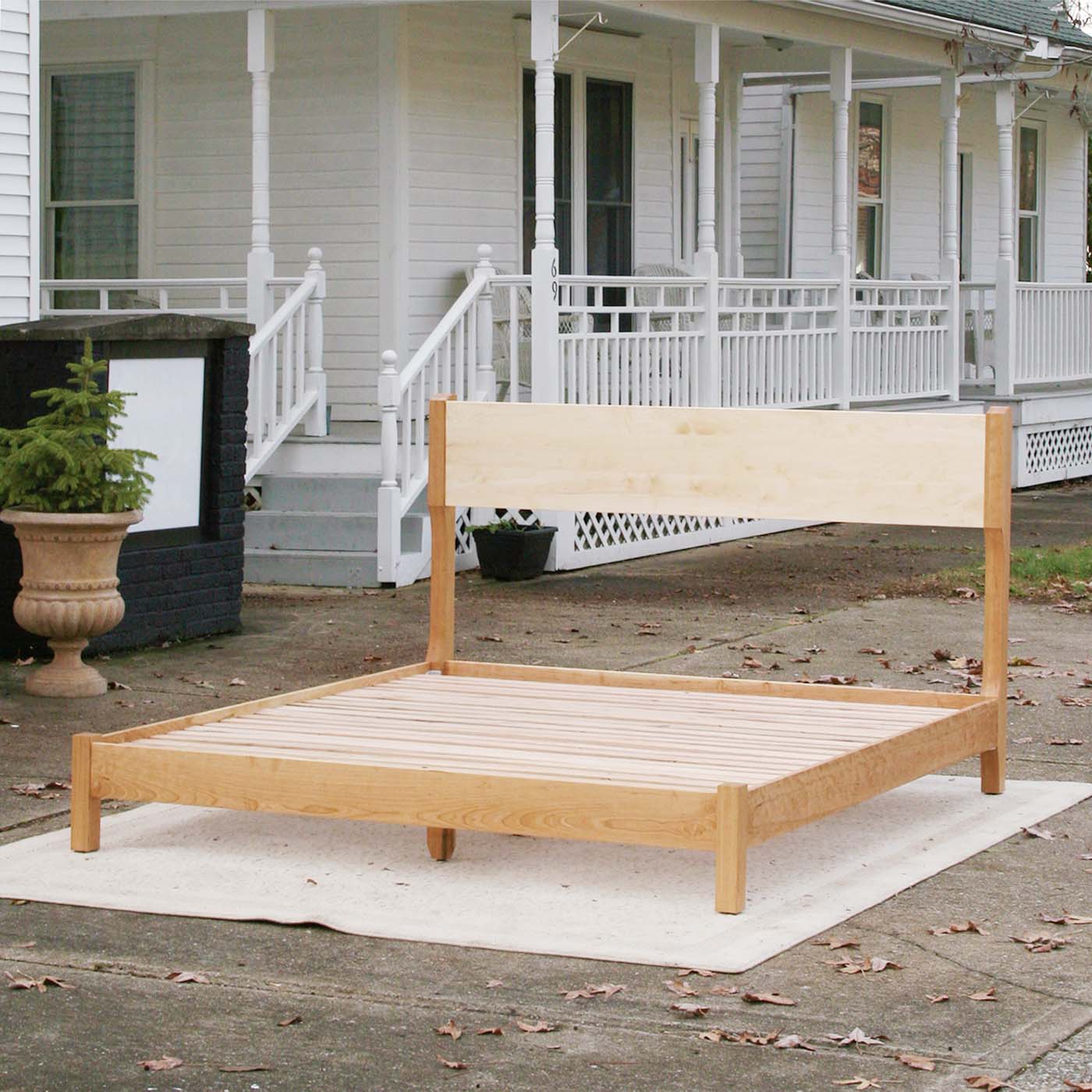 angled view platform bed with tall headboard and curved posts