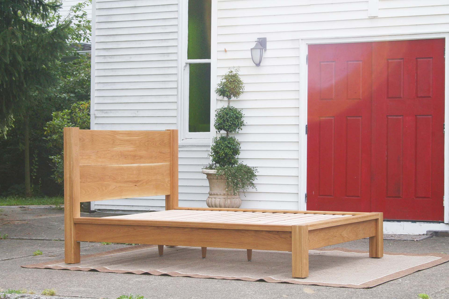 low angled view natural platform bed with thick posts and vertical headboard