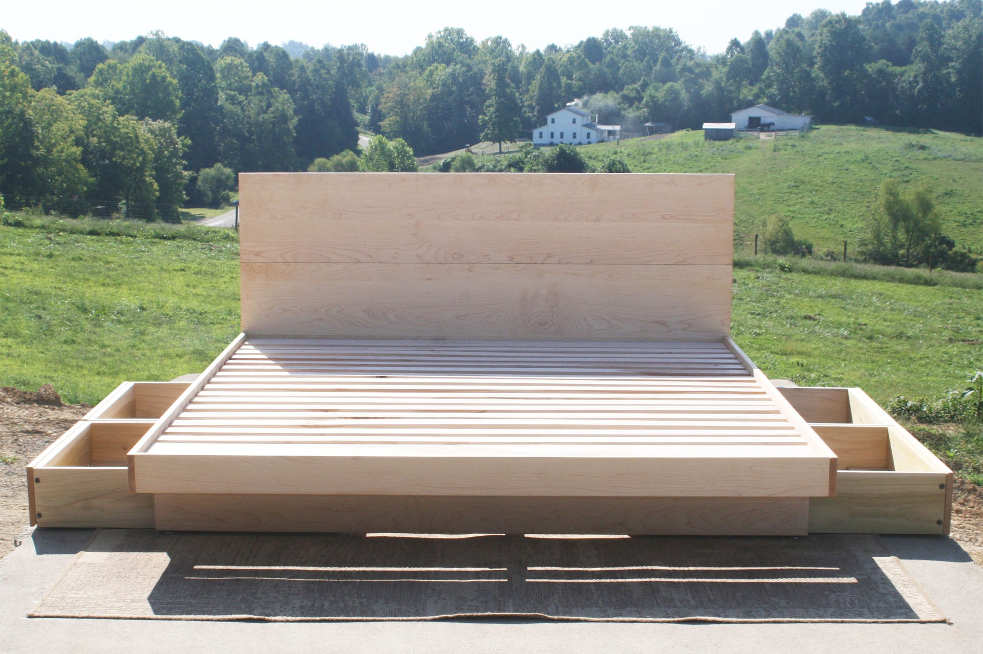 Wooden bed frame with storage drawers in a rural setting