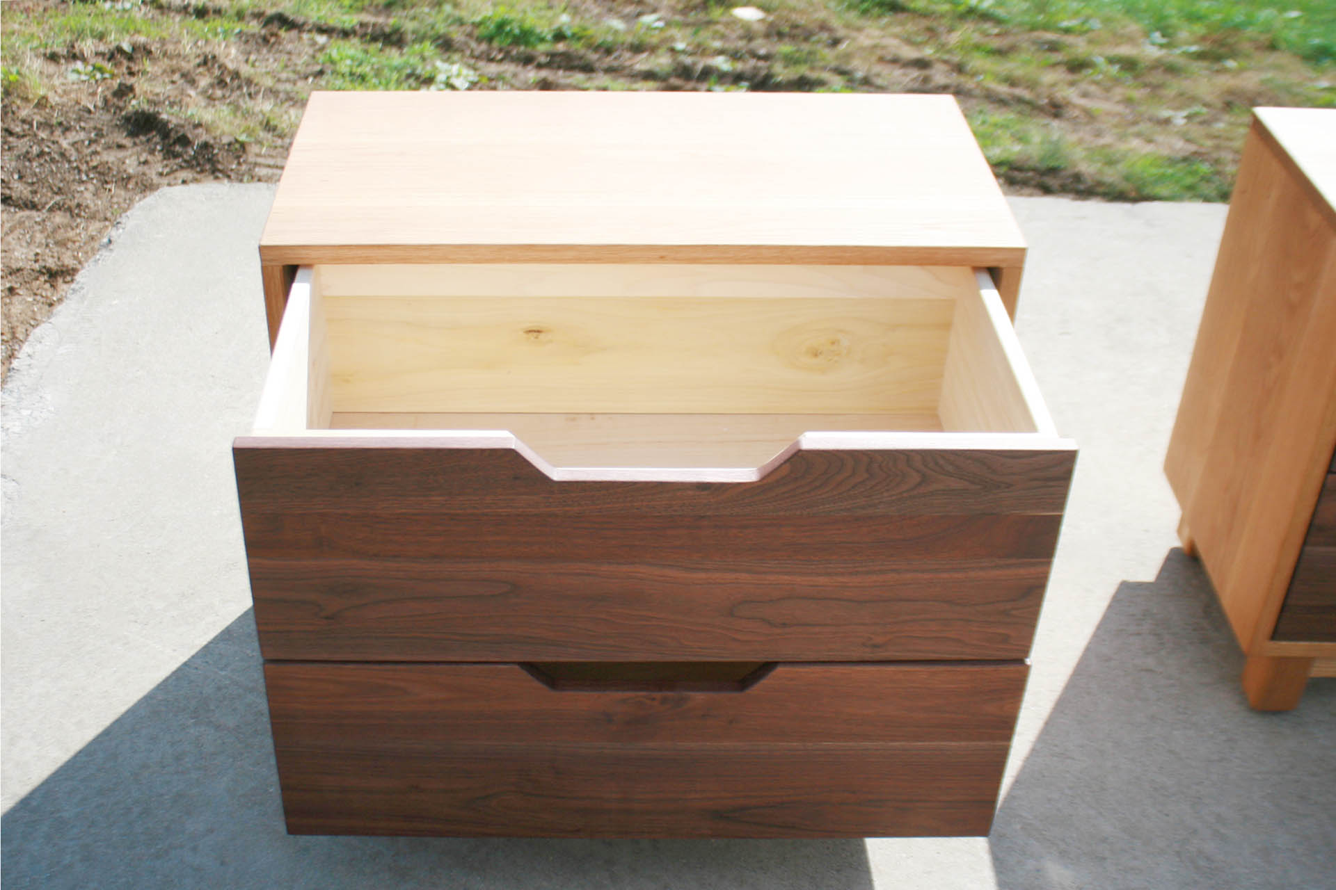 Bedside cabinet with slanted cut pulls drawer open front view
