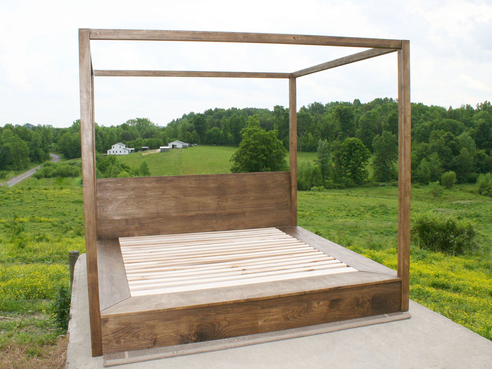 front view of solid low canopy bed with platform extensions and headboard