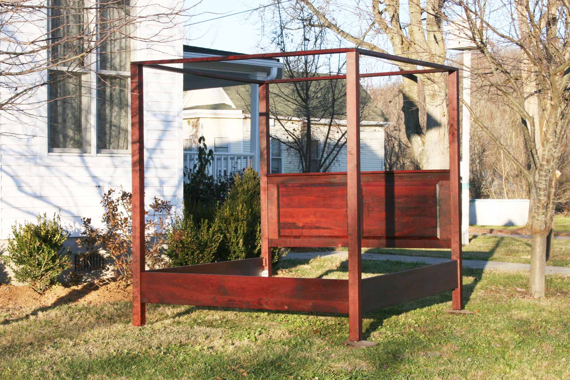angled view hardwood canopy bed with straight posts and paneled headboard