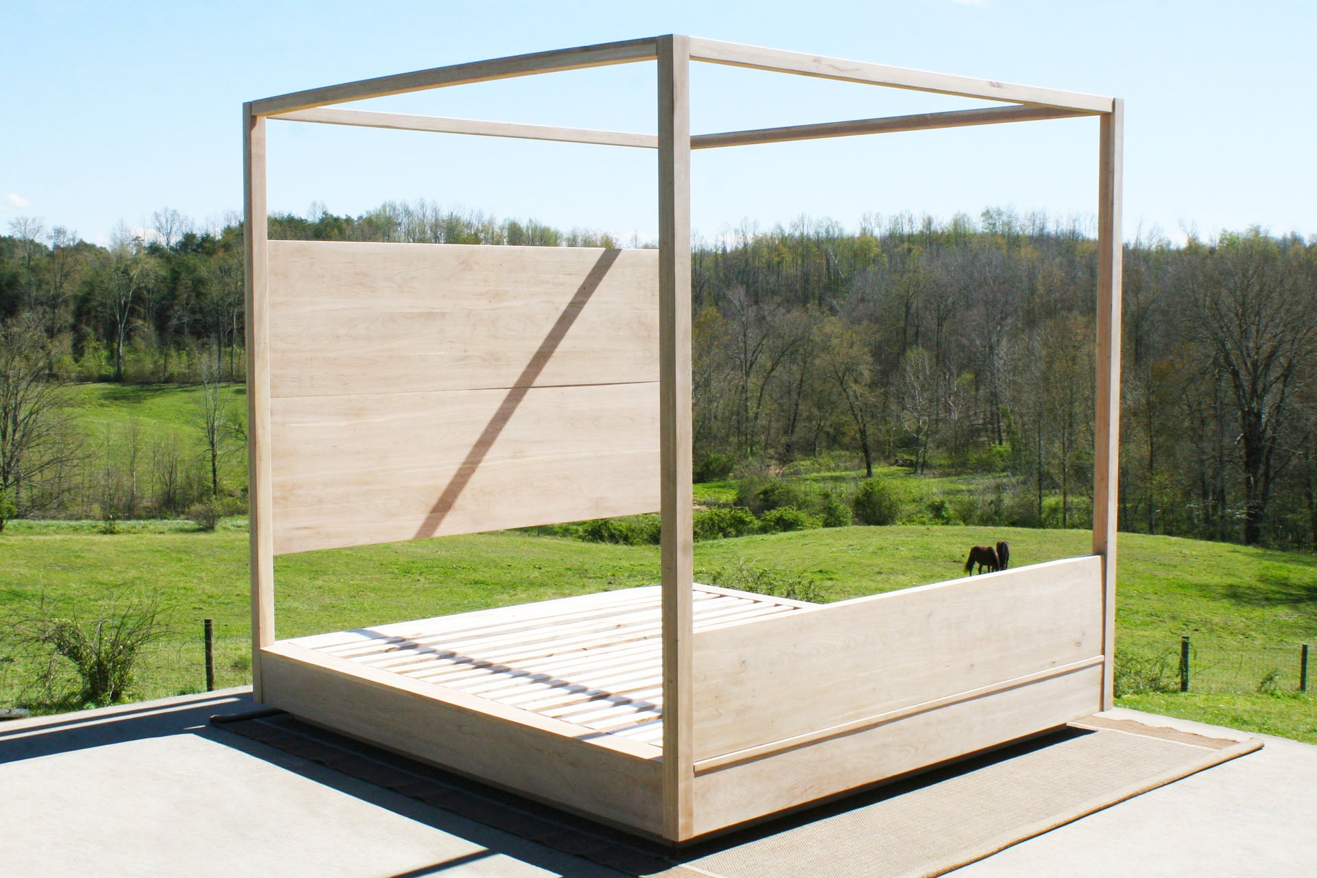 angled view solid canopy Bed with large rail and suspended headboard