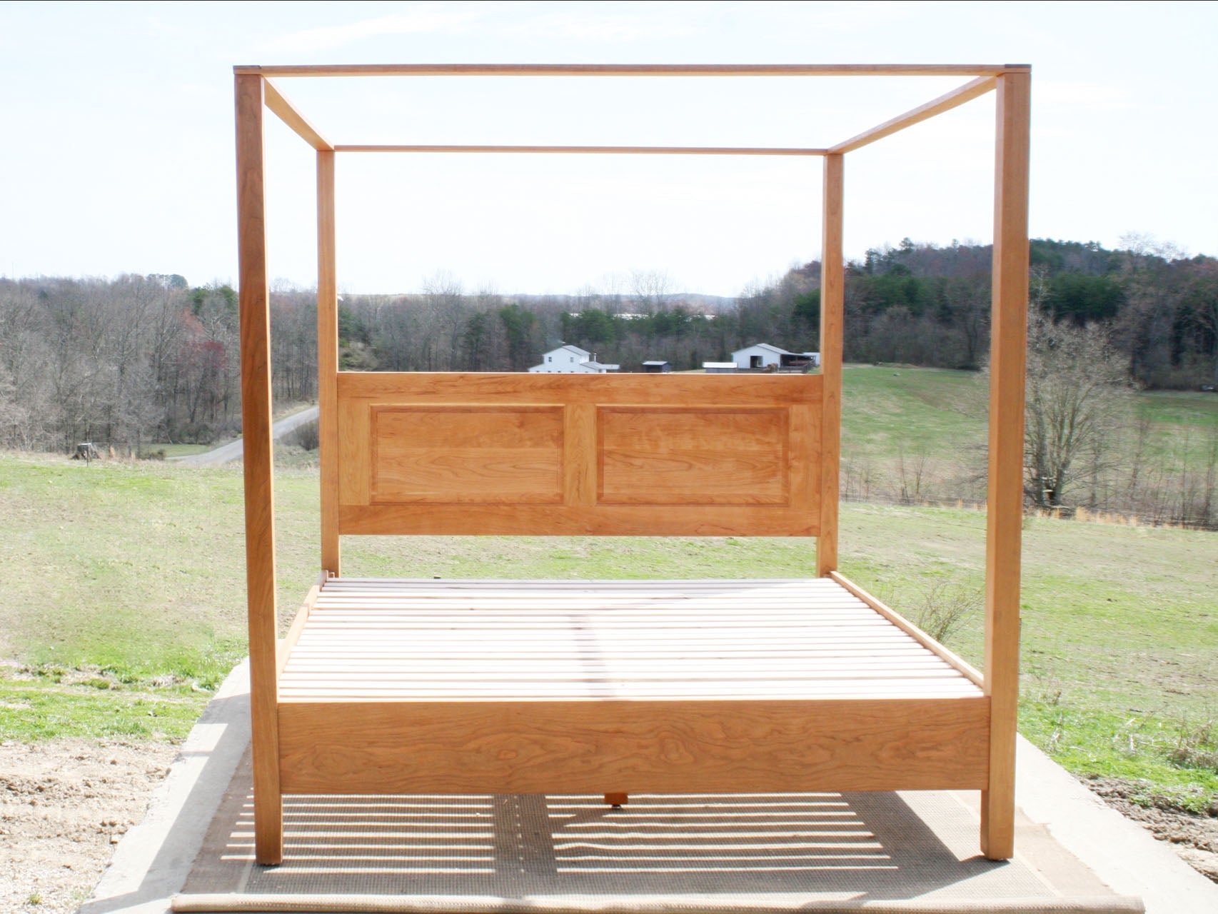 front view of wood canopy bed with headboard