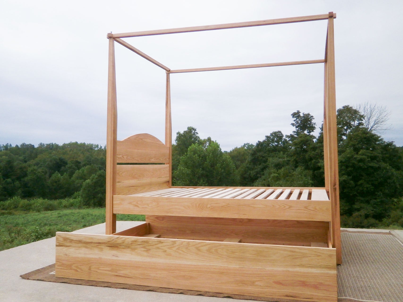 Canopy bed with trundle and arched headboard and trundle bed open