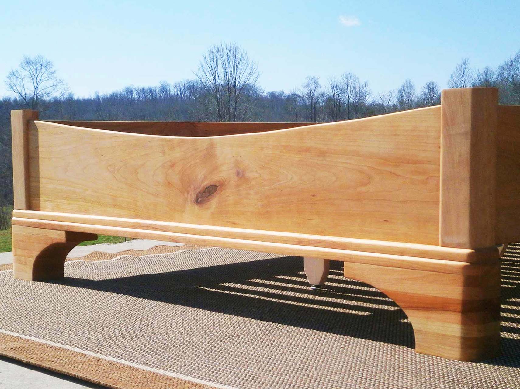 Platform Bed with large block feet and arched ends low angled view natural