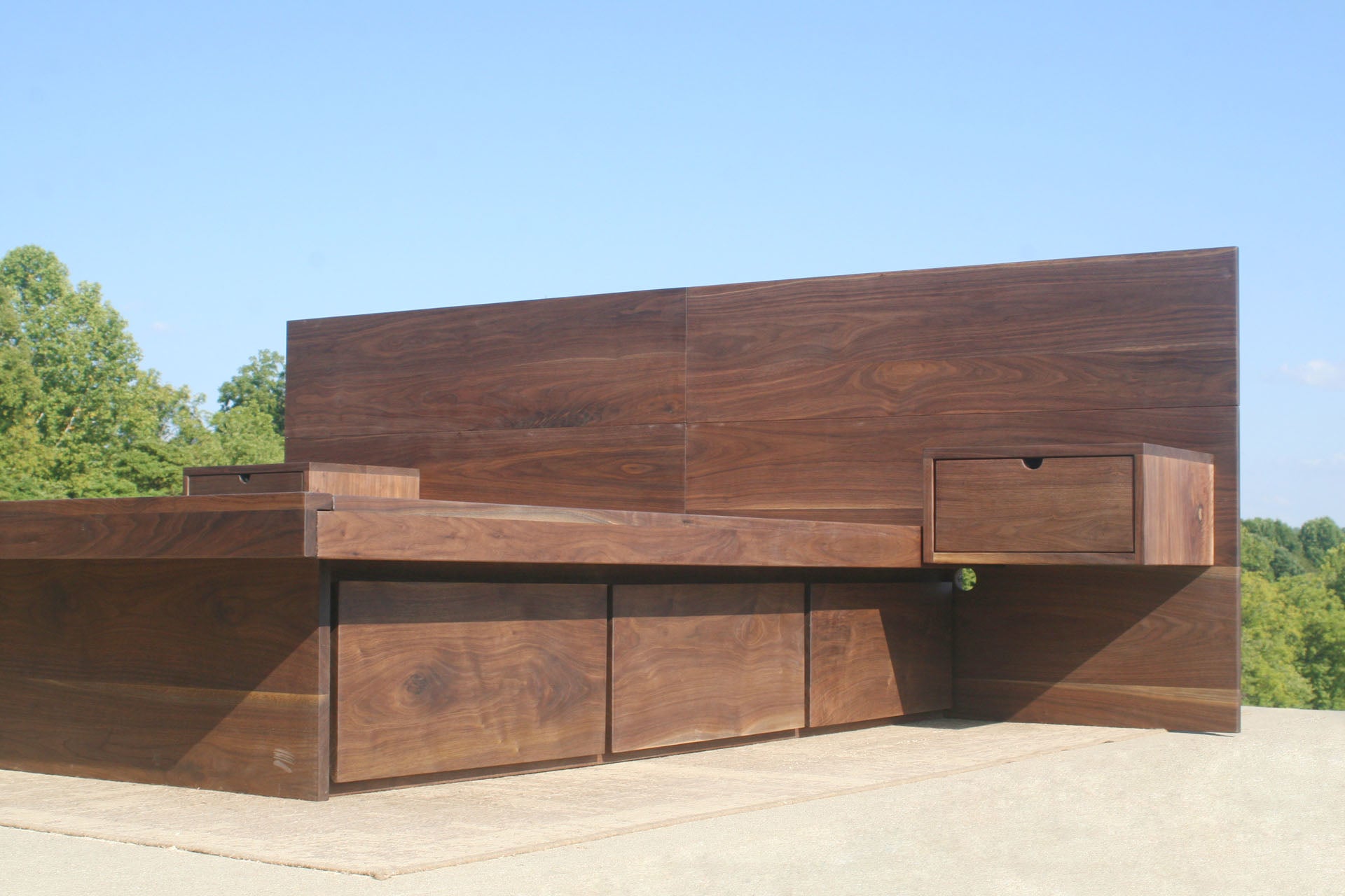 low angled view walnut Storage bed frame with headboard and nightstands