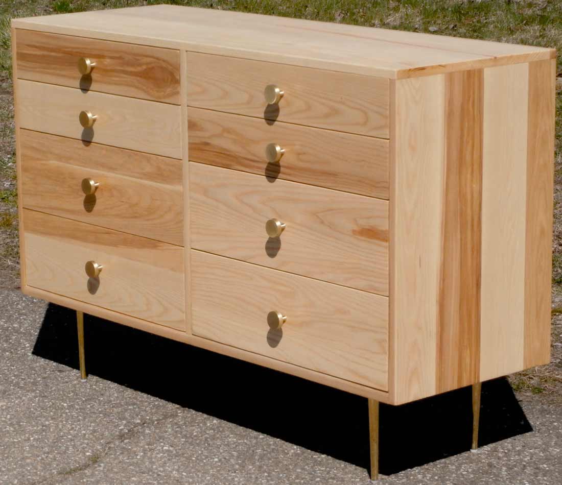 close up angled view dresser with 8 inset drawers and mid century modern polished brass legs and drawer pulls