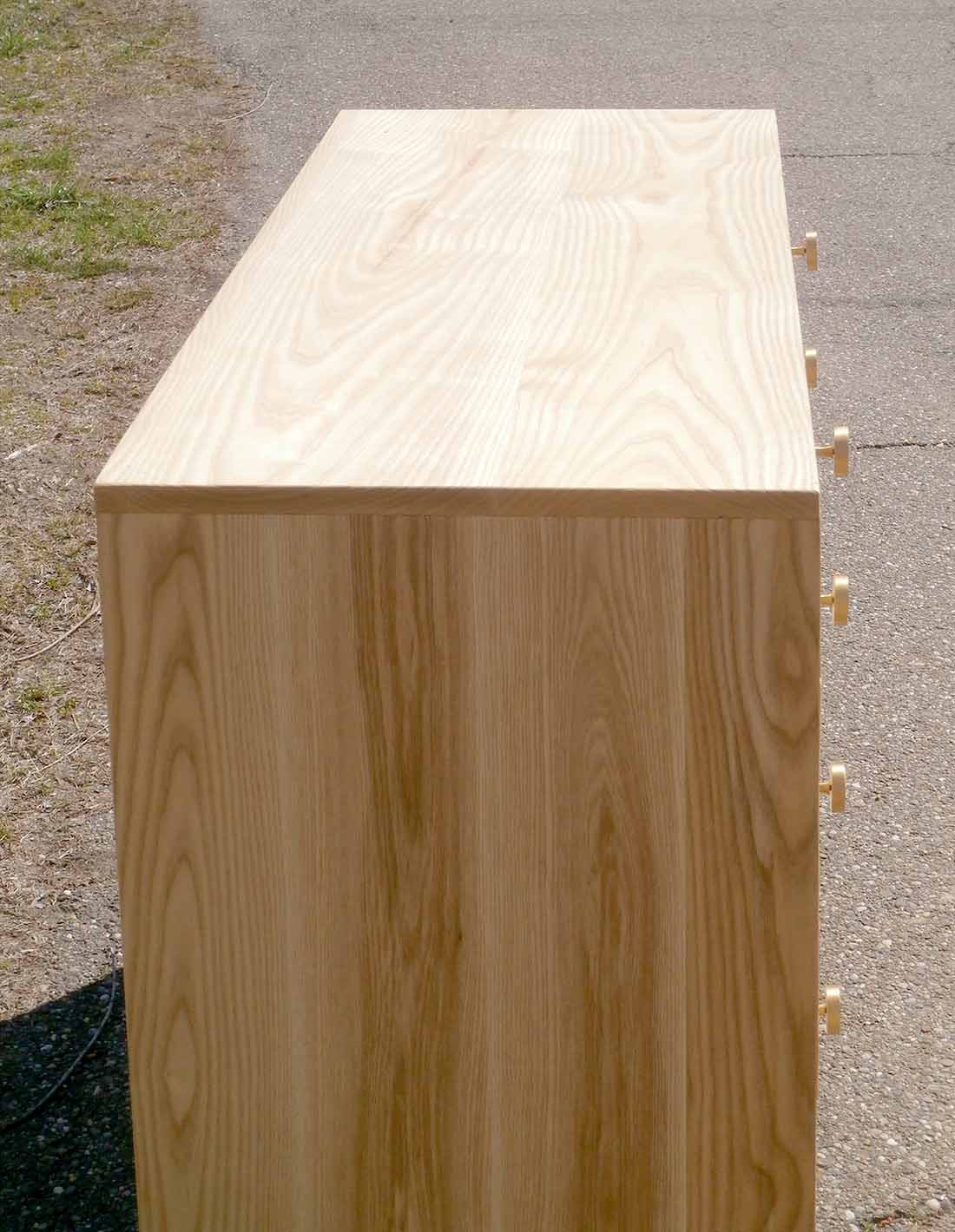 close up side view dresser with 8 inset drawers and mid century modern polished brass legs and drawer pulls