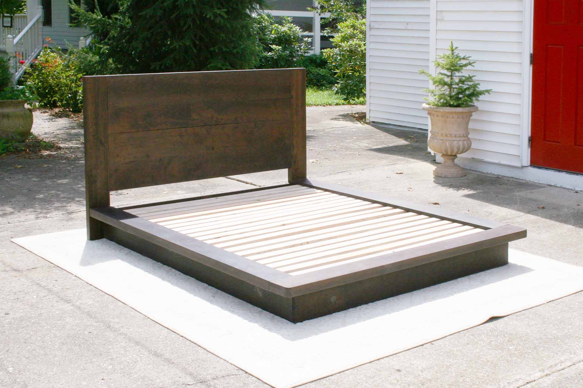 Platform bed with tall headboard and wide sides in walnut angled view