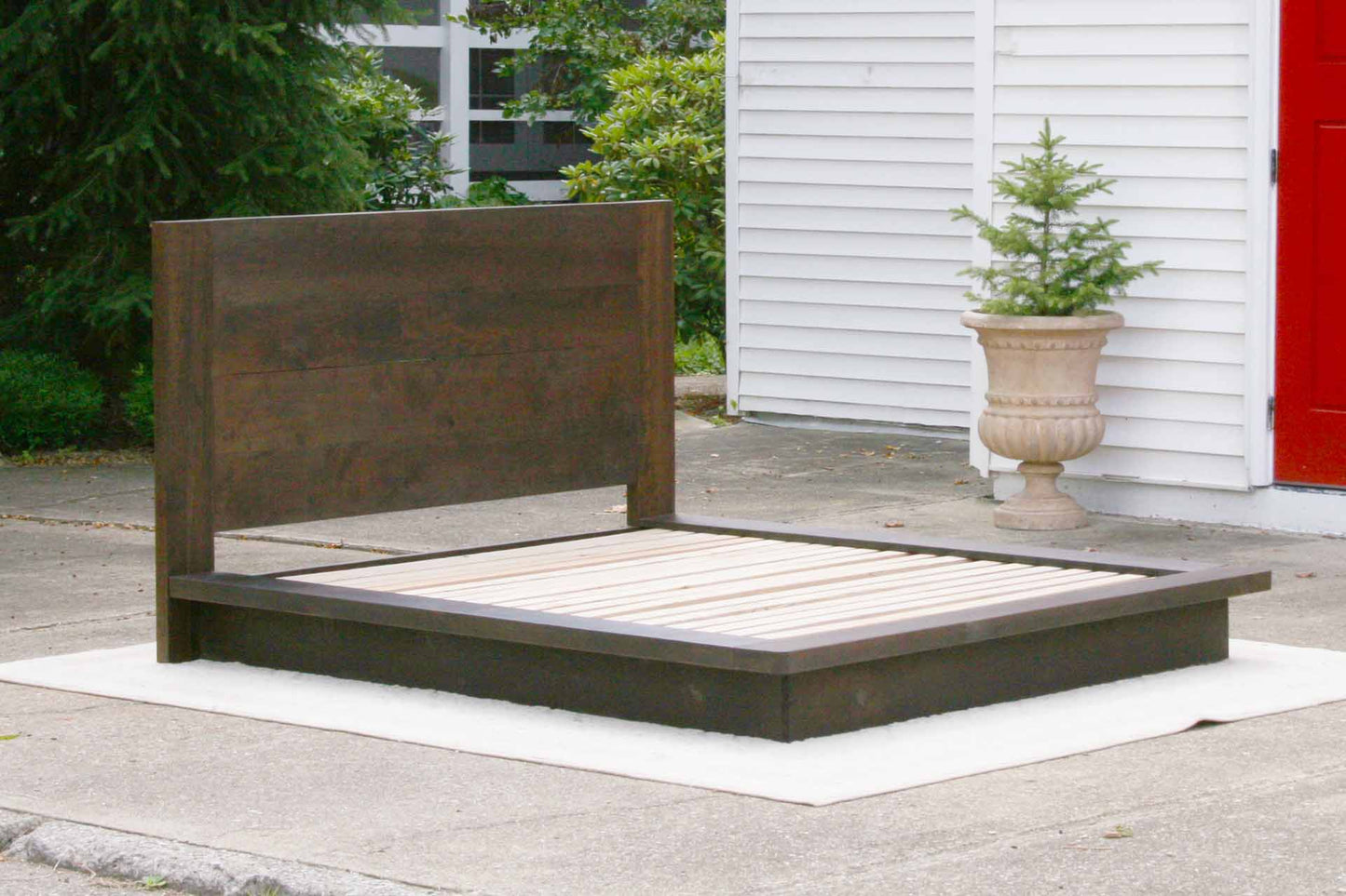angled view Platform bed with tall headboard and wide sides in walnut