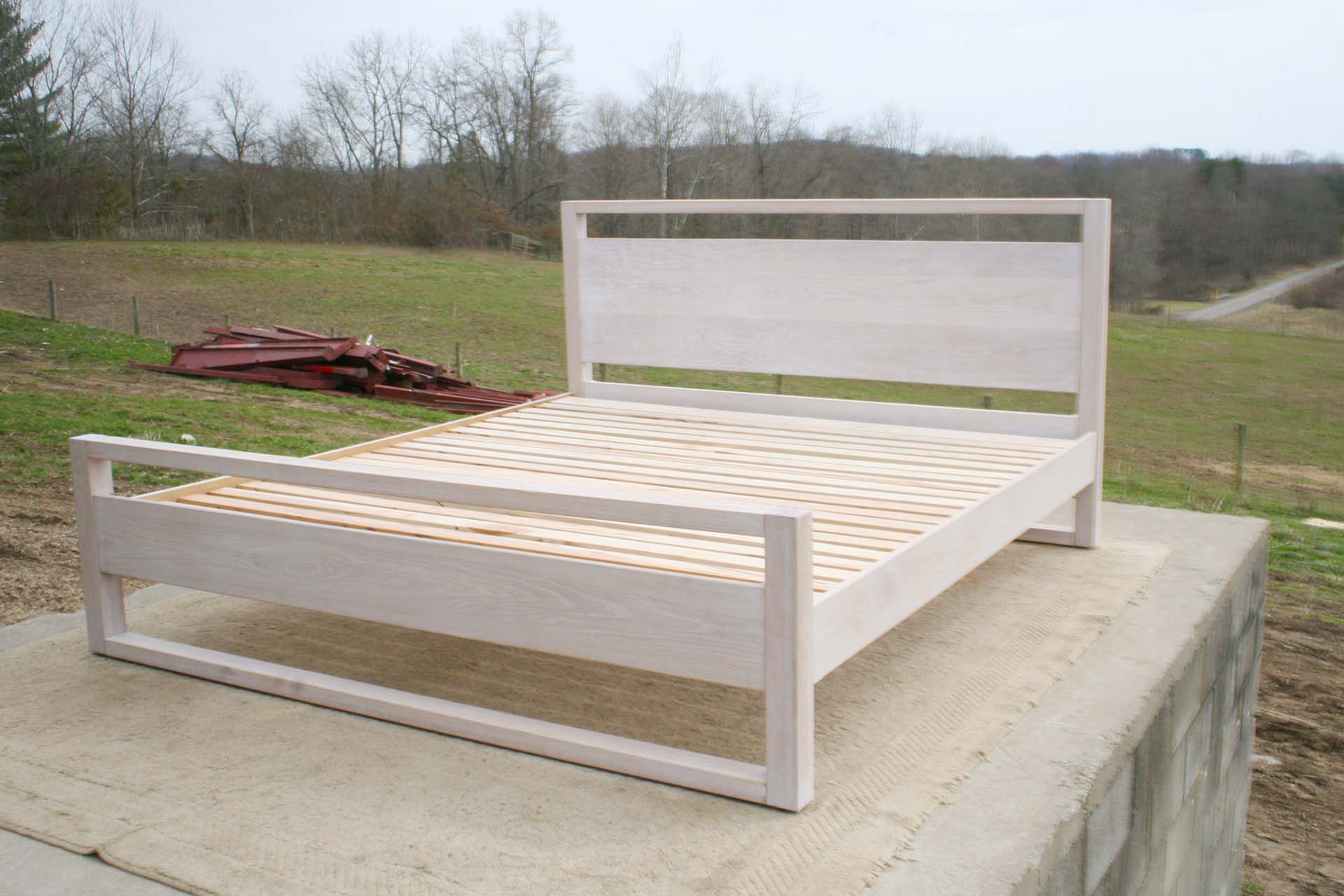 platform bed with a rail above the head board and rails at floor front angled view