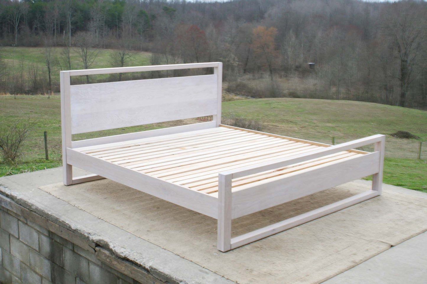 angled view platform bed with a rail above the head board and rails at floor