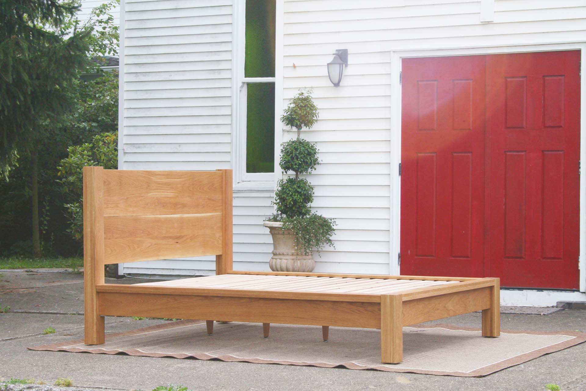 low angled view natural platform bed with thick posts and vertical headboard