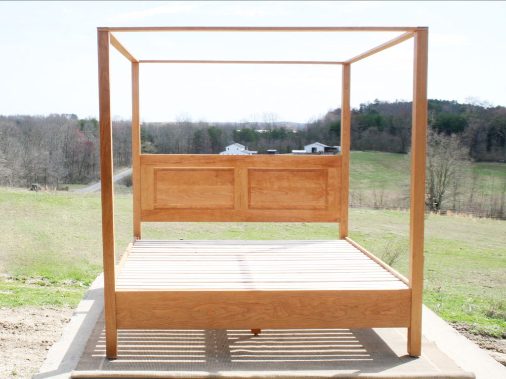 front view of wood canopy bed with headboard